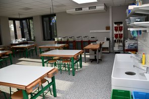 Einblick in eines der Klassenzimmer. Ein Kunst bzw. Werkraum mit Tuschkästen und Waschbecken sowie Gruppentischen.