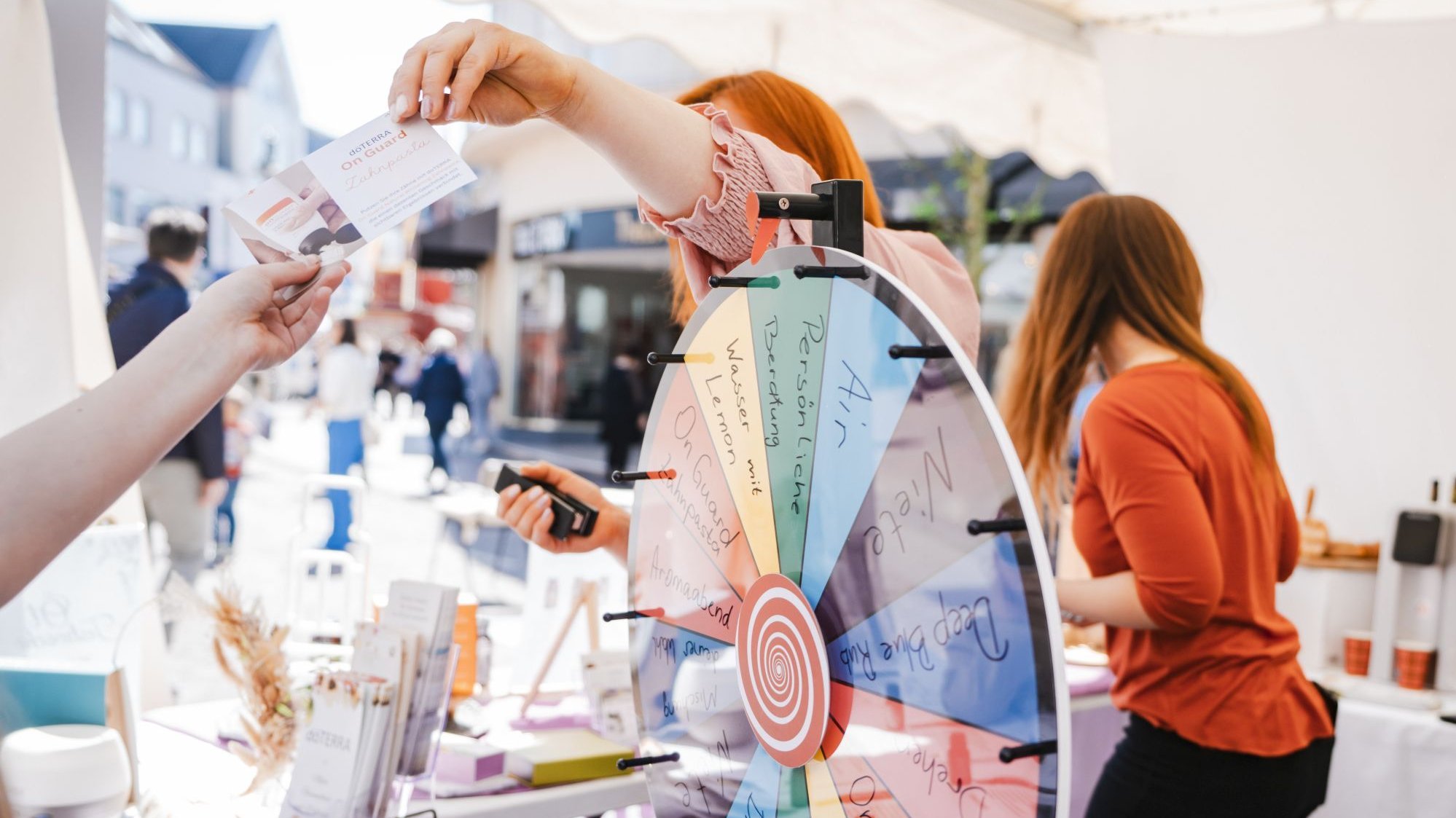 Eine Frau erhält einen Gutschein. Im Vordergrund ist ein Glücksrad zu sehen.