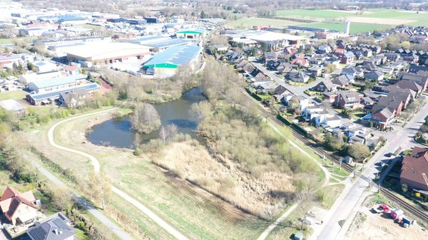 Luftbildaufnahme aus größerer Entfernung. Die umliegende Siedlung und das Industriegebiet sind zu sehen.