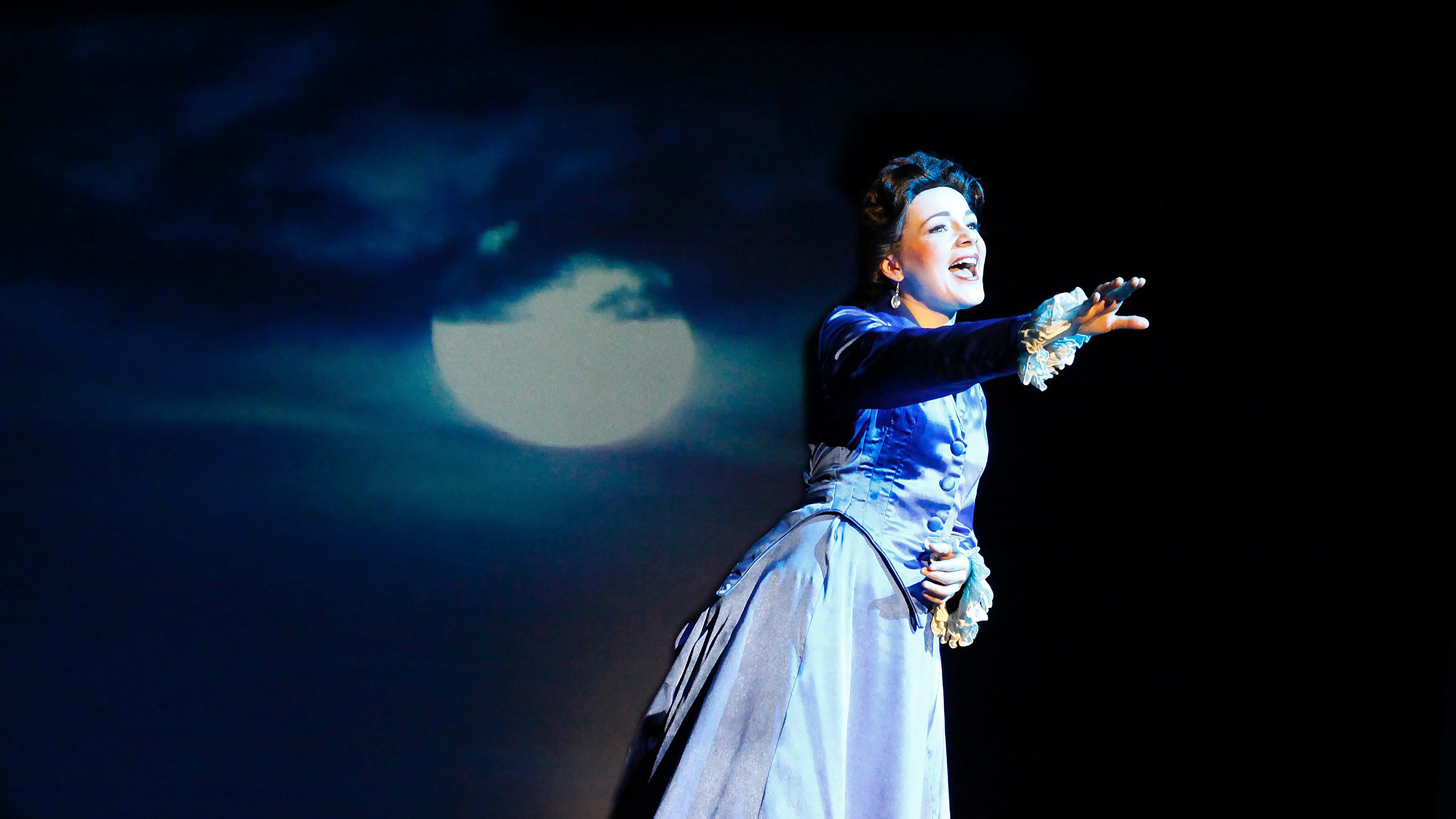 Die Schauspielerin der Sissi steht im Mondlicht der Theaterkulisse und streckt ihre Hand in Richtung Publikum
