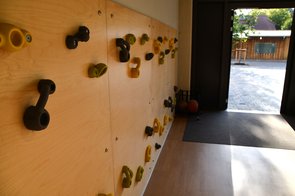 Eine Kletterwand zeigt, dass es innerhalb der Schule auch abseits der Turnhalle Sportmöglichkeiten für Kinder gibt.