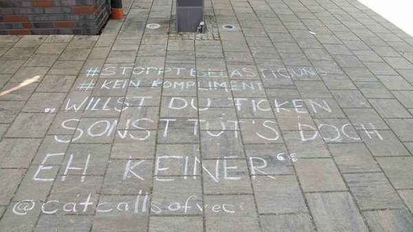 Auf dem gepflasterten Steinboden ist mit Kreide gemalt worden. Dort steht: #stopptbelästigung #keinkompliment "Willst du ficken, sonst tut's doch eh keiner" und @catcallsofvec